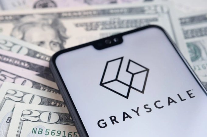 A smartphone displaying the Grayscale logo resting on top of US twenty dollar bills.