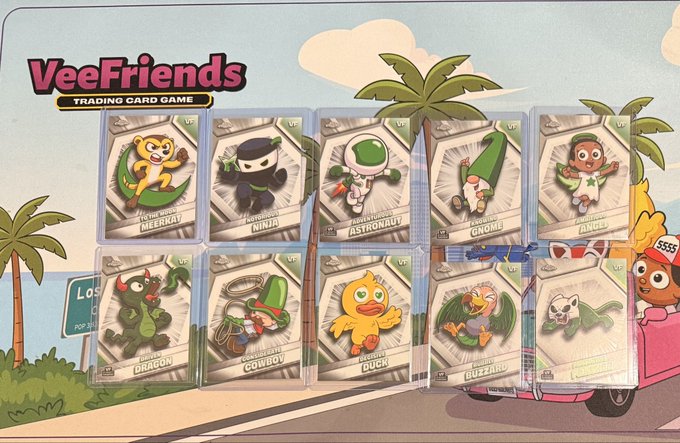 A collection of VeeFriends Trading Card Game cards laid out, featuring characters like Meerkat, Ninja, Astronaut, Gnome, Angel, Dragon, Cowboy, Lucky Duck, Buzzard, and Labrador.