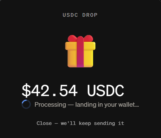 A dark interface displays "USDC DROP" at the top with a gift box icon, showing a $42.54 USDC airdrop in progress with the message "Processing — landing in your wallet..." and an option to "Close - we'll keep sending it." The image humorously illustrates the Moonpay USDC airdrop referenced in the post, depicting the new $42.54 balance ready to be spent.