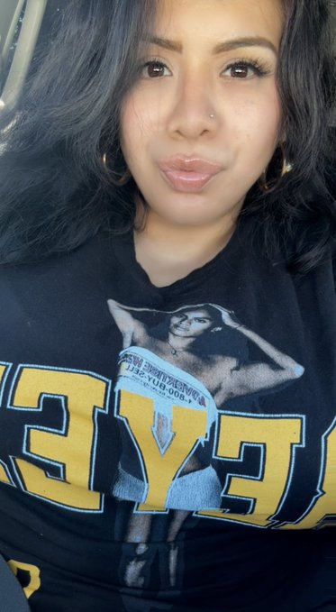 A woman takes a selfie in a black graphic t-shirt featuring "Teyana" in large yellow letters along with what appears to be "Teaquila" and the number "1995," connecting to the post's mention of "Teaquila Time" returning and her emphasis on family.
