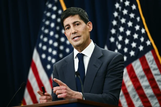 A man in a dark suit speaks at a podium with American flags behind him, gesturing with his hands during what appears to be a Federal Reserve press conference. The image accompanies a post about the FOMC's decision to keep interest rates unchanged for the fifth consecutive meeting, with the speaker likely delivering remarks related to this monetary policy announcement.