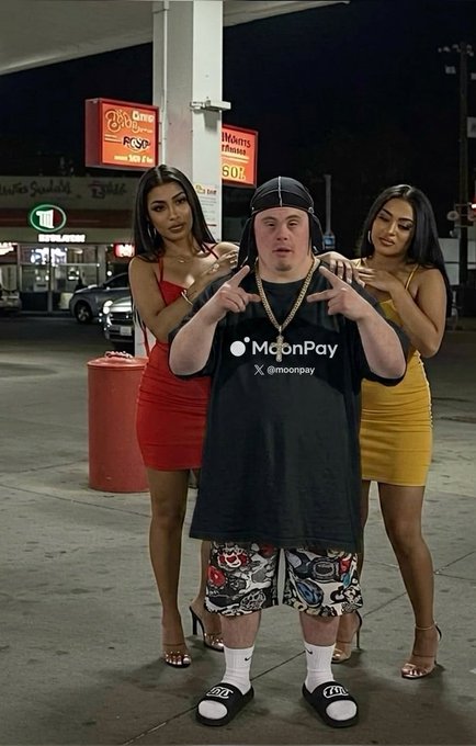 A man wearing a black "MoonPay X @moonpay" t-shirt and a backwards cap stands at a gas station flanked by two women in form-fitting dresses, visually playing on the post's joke that MoonPay has made him so popular that women are "all over" him.