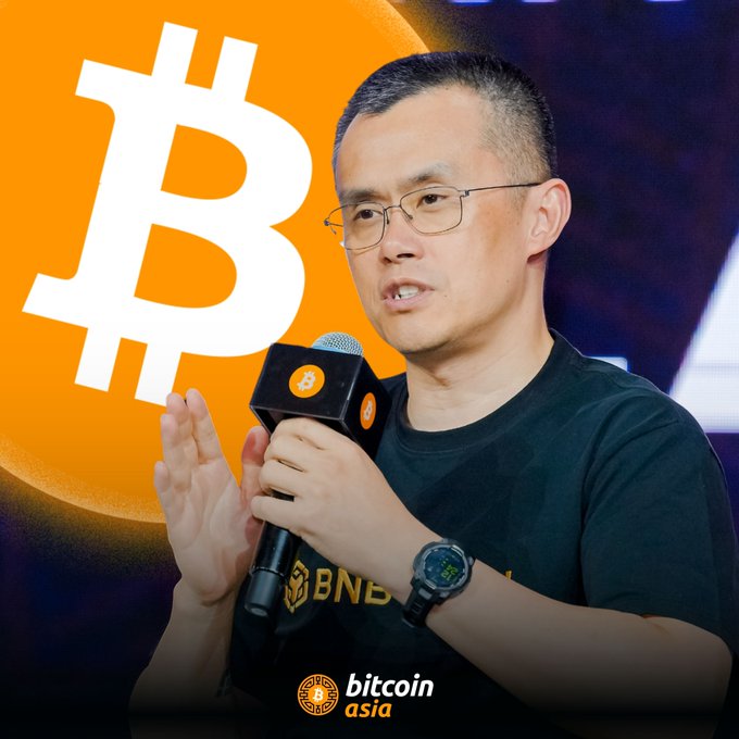 A man with glasses and a black 'BNB' t-shirt speaks into a microphone with a Bitcoin logo, set against an orange background with a large white 'B' symbol, and a 'bitcoin asia' logo at the bottom.