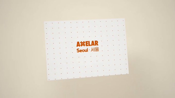 A white card with red dots and the text 'AXELAR Seoul · 서울' in red and orange lettering.