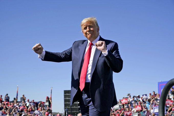 Donald Trump is pictured on a sunny day, perhaps at a rally, with a crowd in the background. The image likely supports the accompanying post by visually representing Trump in the context of discussions about the CLARITY Act and his potential use of the presidency for financial gain.