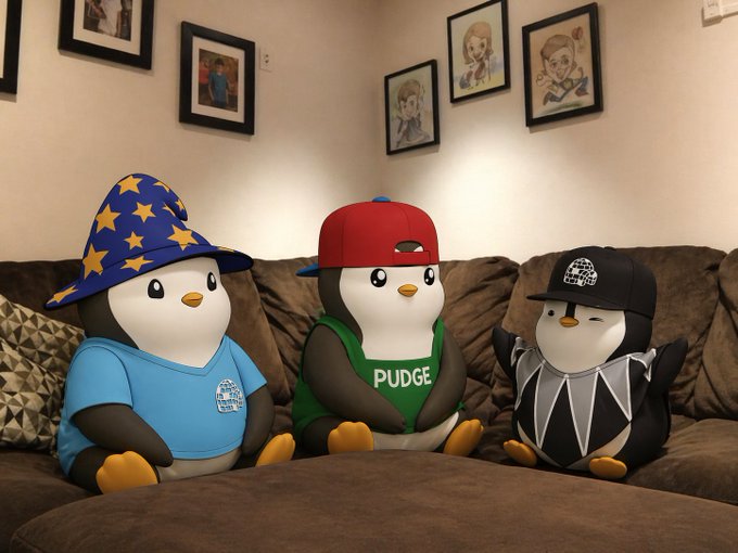 Three cartoon penguins sit on a couch wearing hats and shirts, including one labeled "PUDGE," seemingly gathered for a serious chat—much like the NFT community gathering to debate royalties once more.