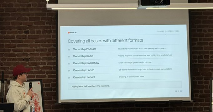 A photograph of a presenter in a red cap speaking next to a slide titled 'Covering all bases with different formats', listing channels like Ownership Podcast, Radio, Roadshow, Forum, and Report.