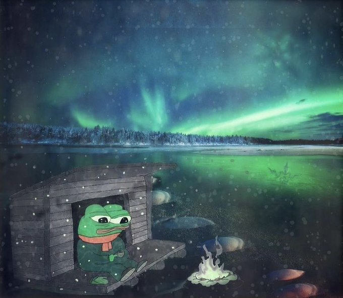 An illustration of Pepe the Frog sitting in a small wooden cabin by a lake, wearing a red scarf with a campfire and aurora borealis in the background.
