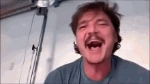iced coffee with a mustache, wearing blue shirt and holding a cup, against a white wall backdrop.