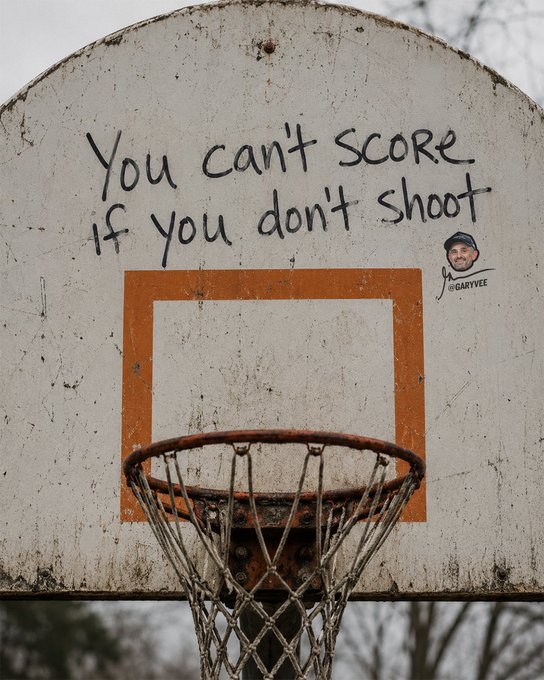 A weathered outdoor basketball backboard displays the handwritten motivational phrase 'You can't score if you don't shoot' along with a '@GARYVEE' sticker.