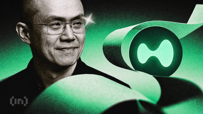 The image features a man wearing glasses standing next to a green paper with a circle cut out of it. The text "Binance founder CZ called Hyperliquid's model" is written above him. Below this, there are two lines of text that read "They don' t have KYC. They claim they're decentralized... I would never do what they do, given what I've experienced..." and "I assume they have good lawyers." The man appears to be smiling at the camera while standing next to the paper with a green circle cut out of it.