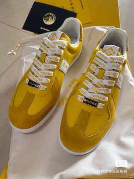 A pair of yellow Diadora sneakers with white laces, placed in front of their branded box and dust bag.