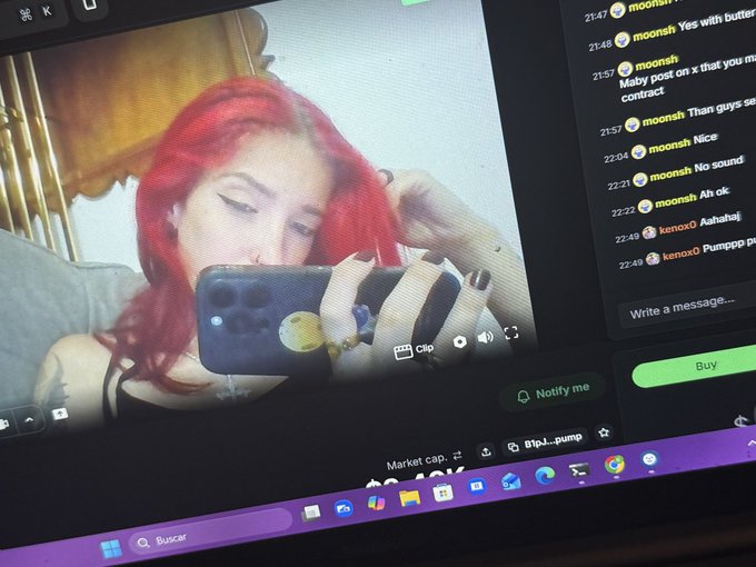A photograph of a computer monitor displaying a video of a red-haired person, alongside a chat window with messages from users 'moonsh' and 'kenox0' and a 'Buy' button.