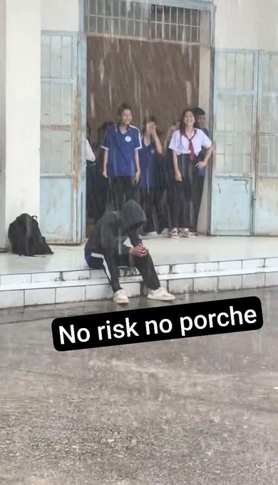 A person in a black hoodie sitting on the steps of a building during heavy rain while others watch from the doorway, with a caption reading 'No risk no porche'.