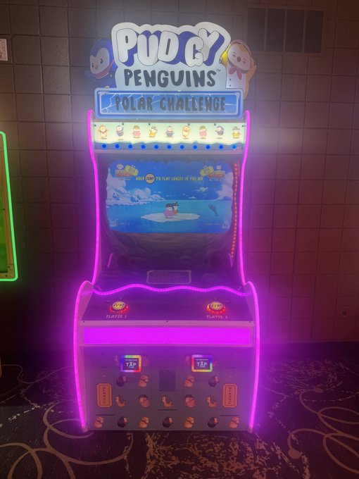 An arcade game machine titled 'PUDGY PENGUINS POLAR CHALLENGE' illuminated with bright pink and blue neon lights.
