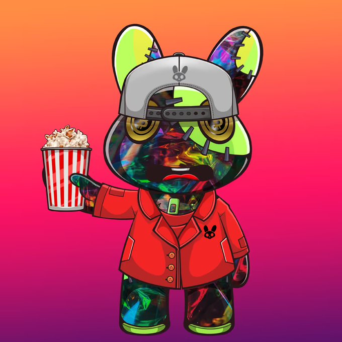 The image features a cartoon character, likely a stuffed animal or toy, wearing a red shirt with white stripes and holding a popcorn bucket. The character appears to be standing against a pink background, which complements its vibrant attire. The caption "Welcome to Dollz Hive!" is written in the bottom right corner of the image, indicating that this artwork belongs to the Dollz Hive website or blog.