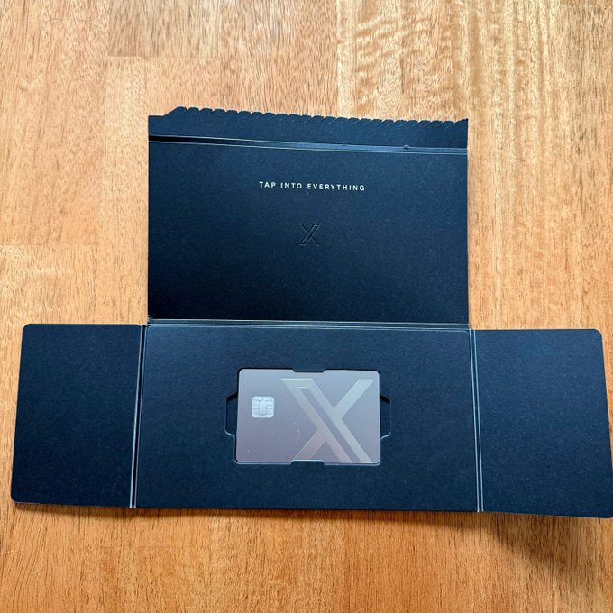 An open black envelope package displays the text 'TAP INTO EVERYTHING' above a card holder containing a metallic card with a large 'X' design and chip, likely an Exodus crypto debit card.
