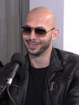 A bald man with sunglasses and a goatee, wearing a black leather jacket, smiles while speaking into a microphone during what appears to be an interview or podcast appearance. The image complements the post's caption, which features a quote attributed to Tristan Tate discussing Bitcoin wealth goals and financial ambition.