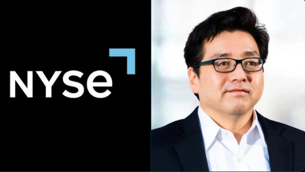 The image features an Asian man wearing glasses standing next to a large NYSE logo, which is black with white text. Above him, there is a smaller font of "Wall Street just found a massive new way to buy $ETH". The NYSE logo includes a blue arrow pointing upwards above it. This scene likely represents a promotional image for Wall Street's new investment strategy in buying Etherium using the NYSE platform.