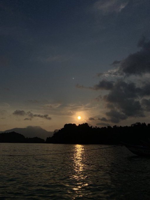 The image shows a beautiful sunset over a body of water, with the sun setting behind some clouds. The sky has a mix of blue and orange hues as the sun sets. In the background, there are mountains visible, adding depth to the scene. The photo is captioned "Good Night CT Wishing you a night full of sweet dreams @River4fun $RIVER". This post seems to be about a boat or a river, possibly suggesting that someone has posted this image on social media with a caption related to boating or water activities.