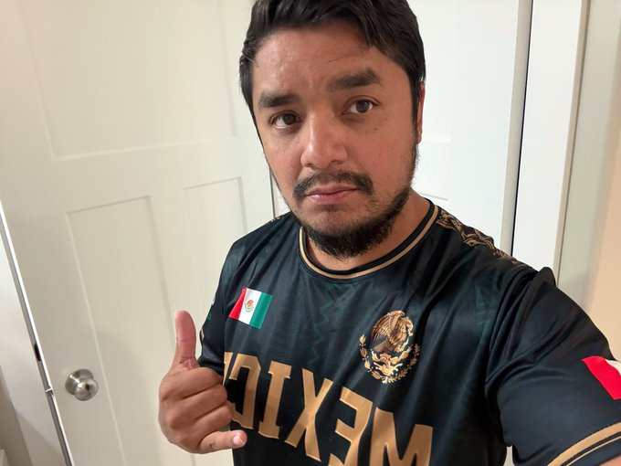 The image features a man wearing a black shirt with gold lettering, which has "Mexico" written across the front of it. The man is giving a thumbs-up sign while posing for the photo. The caption below the image reads "#mexico delivered Today. Tomorrow #USA will lock in".