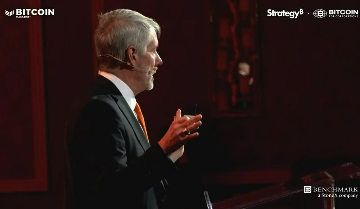 The image shows an older man wearing a suit, standing at a podium with his hands raised while giving a speech or presentation. The caption of the image reads "I understand why they sell Bitcoin but him being a condescending asshole to people saying only idiots would think the company would never sell". This statement suggests that the speaker is trying to make a point about the value and potential of Bitcoin, despite the negative perception some people may have towards it due to the man's behavior.

The image also includes a logo for Benchmark Stocks Company, which further supports the idea that this speech might be related to Bitcoin or cryptocurrency in general. The presence of such a company indicates that there is an interest in investing in Bitcoin and other cryptocurrencies among the audience members who are listening to the speaker's presentation.
