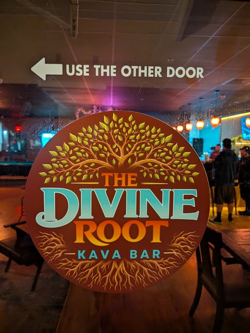 A logo for 'THE DIVINE ROOT KAVA BAR' featuring a tree with extensive roots, with an overlay text reading 'USE THE OTHER DOOR' with a left-pointing arrow.