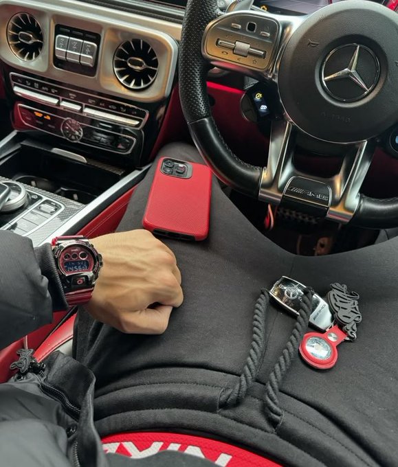 A first-person view from the driver's seat of a Mercedes-AMG shows a wrist flexing a red and black G-SHOCK watch alongside a red iPhone and a keychain featuring a Web3-inspired ghost logo, fitting the "Good morning web3 / Gm if you gm" greeting with an automotive, on-the-go crypto vibe.