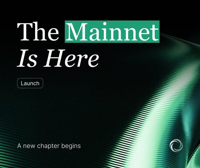 A promotional graphic with a dark green abstract background reading 'The Mainnet Is Here' with a 'Launch' button and the tagline 'A new chapter begins' at the bottom.