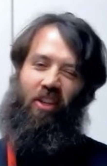 A blurry close-up photo of a bearded man with long dark hair, appearing to be a well-known meme image.