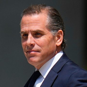 A close-up photograph of Hunter Biden wearing a dark suit, white shirt, and black tie.