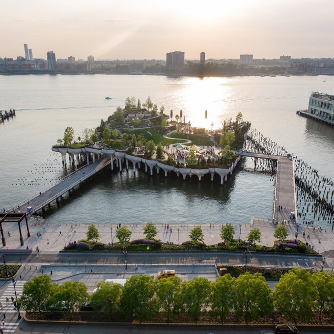 A scenic aerial view of an artificial island park on the water, featuring lush greenery, walking paths, and distinctive curved architectural elements, with a city skyline in the background at sunset. The connection to the post isn't directly visible in the image, as there are no identifiable text, signs, or brand references like Coinbase—suggesting the caption may be referencing a private joke or off-screen context rather than visible content.