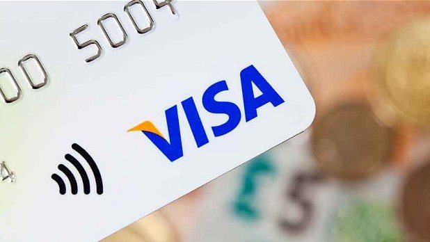 A close-up of a Visa credit card showing the blue and gold Visa logo, a contactless payment symbol, and the digits '00 5004' embossed on its surface.