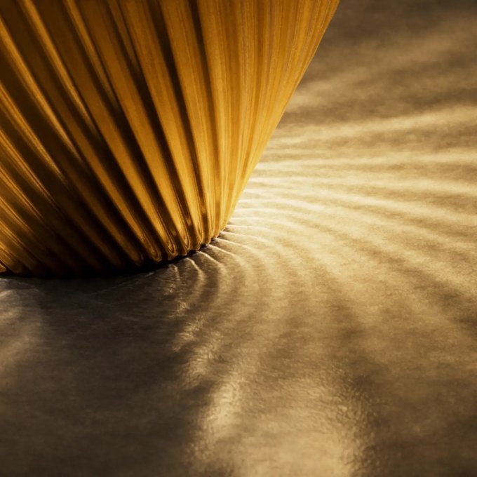 An abstract artistic image showing golden-yellow strands or fibers radiating from a point and casting wavy, linear shadows on a textured surface, with a warm monochromatic color scheme.