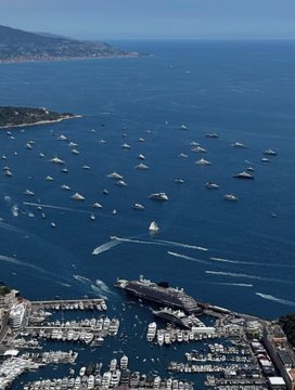 The image shows a large body of water filled with numerous boats, including yachts and sailboats. The boats are scattered across the water, creating an impressive scene that captures the essence of boating activities. The photo appears to be taken from an aerial perspective, providing a comprehensive view of the harbor and its surroundings. The post accompanying this image is titled "Monaco GP weekend. More yachts than fish out there. IRL Bored Ape Yacht Club." This title suggests that the location might be in Monaco or another similar city where boating activities are popular.