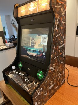 Another view of the same 'UNCONTROLLER' arcade machine showing its side panel artwork and the game display screen with the QR code.