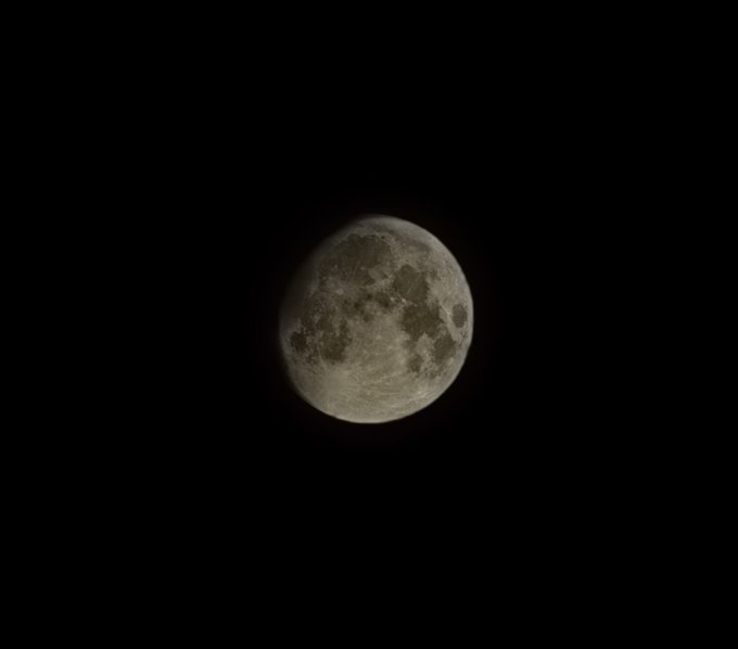 A waxing gibbous moon is visible against a pitch-black night sky.