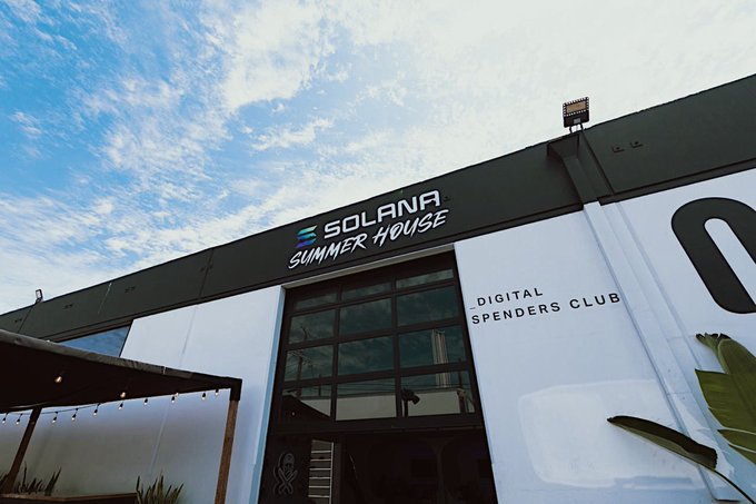 A modern building exterior features signage reading 'SOLANA SUMMER HOUSE' and 'DIGITAL SPENDERS CLUB' against a partly cloudy sky.