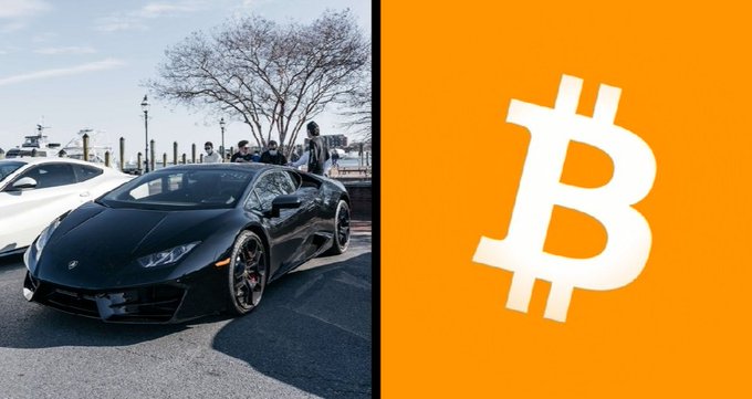 A black Lamborghini is parked on a city street next to an orange panel displaying the Bitcoin (₿) logo, visually representing the caption's announcement that Lamborghini dealers across the U.S. now accept $BTC as payment for their iconic supercars.