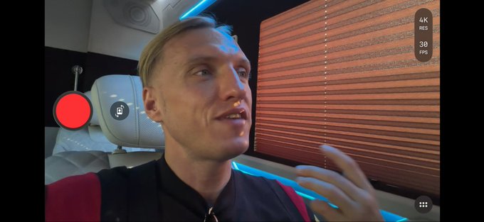 A blonde man speaks to the camera inside a vehicle featuring wooden blinds and blue LED lighting, with a recording interface showing "4K RES" and "30 FPS" in the top right corner. The setting suggests a vlog-style video presentation, likely related to the Bitcoin warning mentioned in the accompanying post.