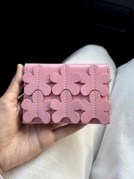 A hand holds a pink quilted wallet with a floral embossed pattern inside a car. The post likely refers to the image since the user feels "so unlucky" despite the wallet being an attractive accessory.