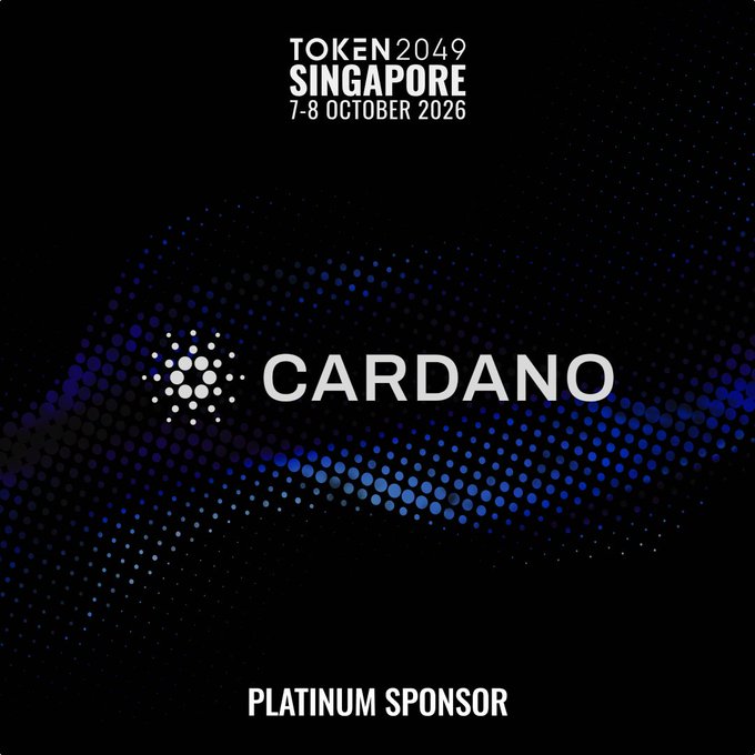 A promotional graphic featuring the Cardano logo as a Platinum Sponsor for TOKEN2049 Singapore (7-8 October 2026), with the tagline "PLATINUM SPONSOR" at the bottom, announcing Cardano's presence at booth PB5-60 as a research-driven, proof-of-stake Layer 1 blockchain serving as digital trust infrastructure.