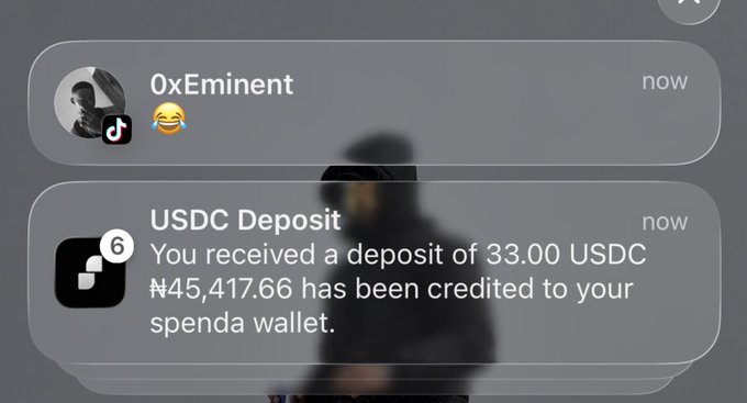 A blurred person appears behind smartphone notifications showing a message from "0xEminent" with a laughing emoji and a "USDC Deposit" alert confirming that 33.00 USDC (₦45,417.66) has been credited to their Spenda wallet, supporting the post's call for users to share their Spenda activity.