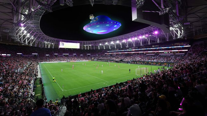 iced stadium with purple and blue lights, green field, and spectators filling stands during a soccer match.
