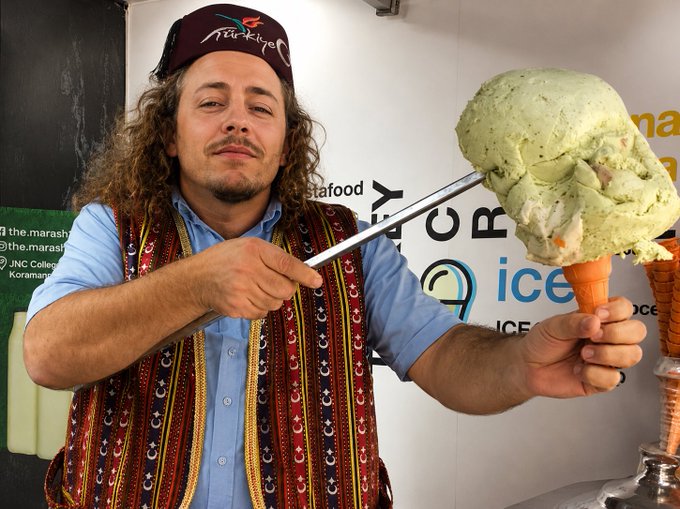 A man wearing a "Turkey" cap and a traditional vest proudly holds up a massive scoop of green ice cream on a cone, playfully embracing the post's humorous bet to open an ice cream stand in Turkey if the US loses.