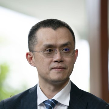 The image shows a man with short dark hair, wearing glasses, a dark suit, white shirt, and blue striped tie, appearing to be in a professional setting.

The post quotes CZ (Changpeng Zhao), the former CEO of Binance, suggesting the image is meant to represent him as the source of the wisdom about patience in crypto investing.