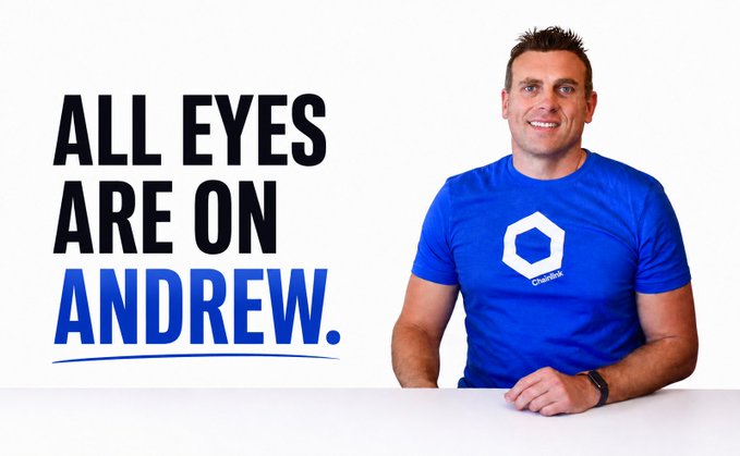 A smiling man in a blue Chainlink t-shirt sits at a table alongside bold text reading "ALL EYES ARE ON ANDREW," visually framing the post's message about the responsibility of winning back a community. The "ALL EYES ARE ON ANDREW" headline reinforces the central theme of him being tasked with reversing the "token not" sentiment and re-energizing the project's community.