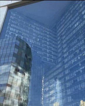A towering glass skyscraper with a distinctive curved, warped section protrudes from its facade, set against a blue sky with reflections visible on the building's windows. The image illustrates the engineering marvel mentioned about the unique architectural feature at the Poly headquarters, showcasing the remarkable curved glass installation high up on the building.