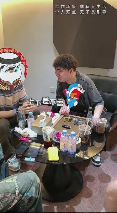 Two men sit at a small round table cluttered with water bottles, iced coffees, and electronic devices, examining a watch with on-screen text reading "上下差不多" (roughly "similar up and down"). The post references encountering a watch-selling influencer and mentions someone who made around $10 million trading coins on BSC, suggesting the scene depicts a discussion about luxury watches and crypto earnings.