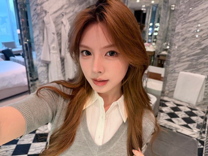 The image features a woman with long brown hair wearing a gray sweater, posing for a photo. She has her arm around herself while looking at the camera. The background of the image includes a bathroom setting with a sink and a mirror. There is also an additional text in the image that reads "Successfully introduced a match for me 4BNB". This suggests that the woman might have recently posted a picture on social media, possibly to share her experience or to recommend a product or service related to the post's content.